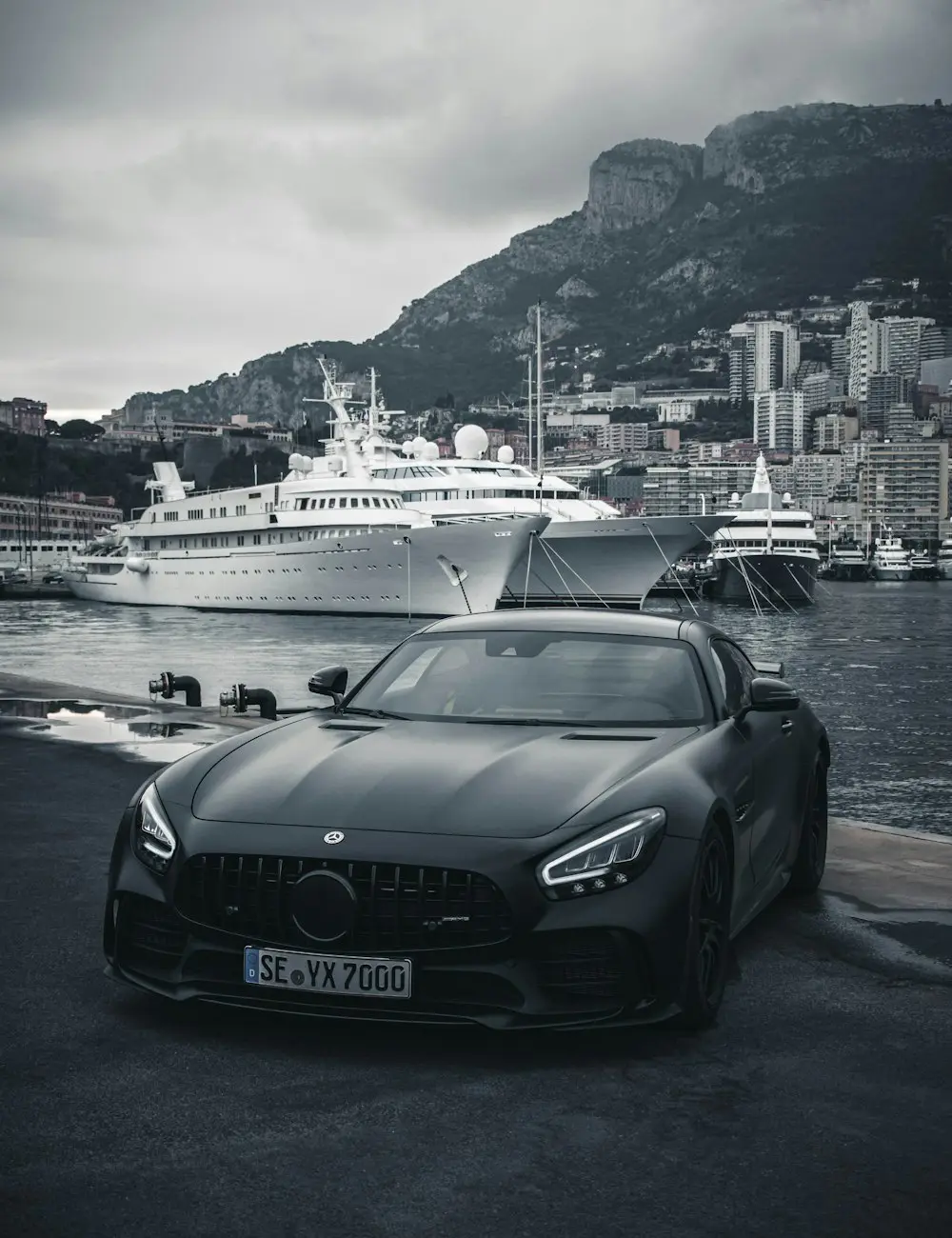 Matt fekete prémium sportautó kikötői környezetben, borús égbolt alatt – illusztráció